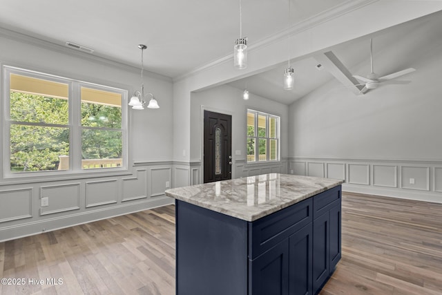 1552 Windsong Dr SW, Ocean Isle Beach, NC 28469 - kitchen featuring blue cabinets, wainscoting, light wood-style floors, lofted ceiling, and pendant lighting