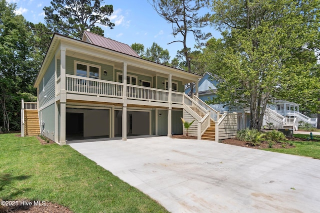 1552 Windsong Dr SW, Ocean Isle Beach, NC 28469 - coastal inspired home with stairway, a porch, concrete driveway, a garage, and a front yard
