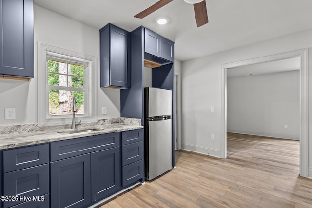 1552 Windsong Dr SW, Ocean Isle Beach, NC 28469 - kitchen with freestanding refrigerator, a sink, ceiling fan, light wood finished floors, and light stone countertops