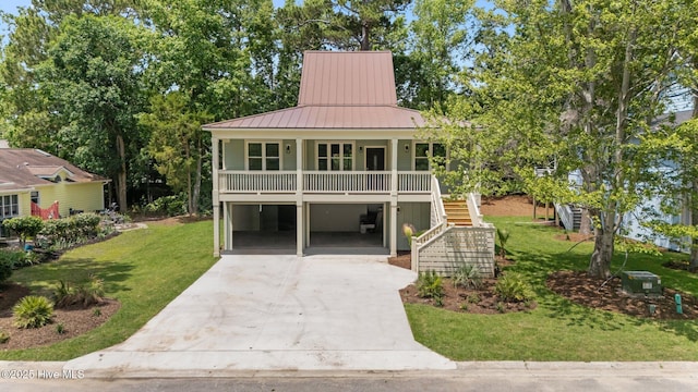 1552 Windsong Dr SW, Ocean Isle Beach, NC 28469 - raised beach house featuring driveway, a front yard, covered porch, a standing seam roof, and stairway