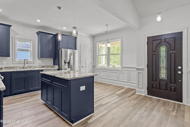 1552 Windsong Dr SW, Ocean Isle Beach, NC 28469 - kitchen with stainless steel fridge, a sink, light wood-style flooring, light stone counters, and a center island