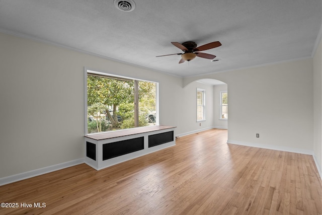 unfurnished living room with ceiling fan, ornamental molding, a healthy amount of sunlight, and light hardwood / wood-style floors