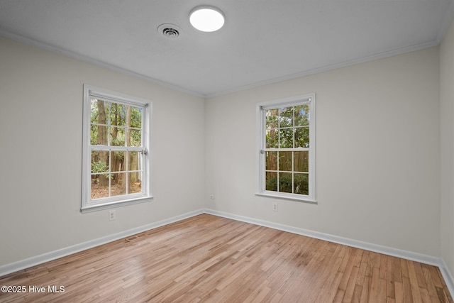 unfurnished room with light hardwood / wood-style floors, a wealth of natural light, and crown molding