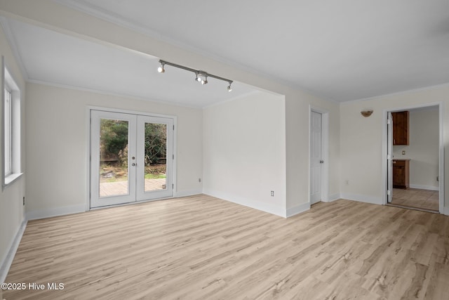 spare room with rail lighting, french doors, crown molding, and light hardwood / wood-style flooring