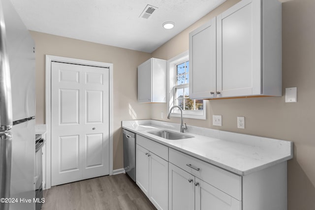 kitchen featuring appliances with stainless steel finishes, white cabinetry, and sink