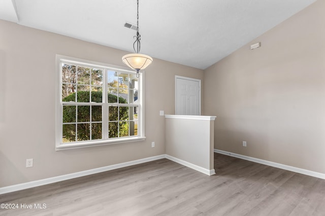 unfurnished dining area with plenty of natural light, light hardwood / wood-style floors, and lofted ceiling