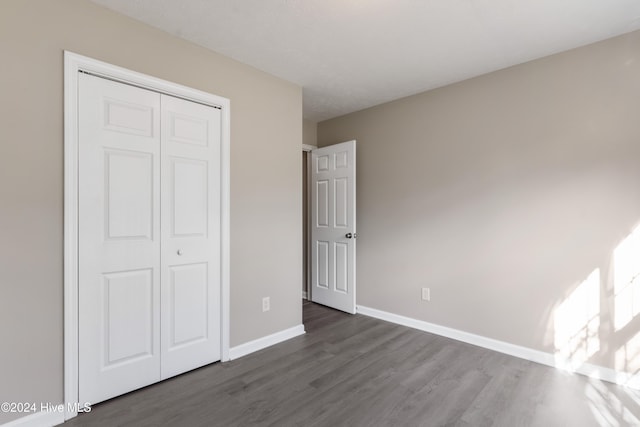 unfurnished bedroom with dark hardwood / wood-style flooring and a closet