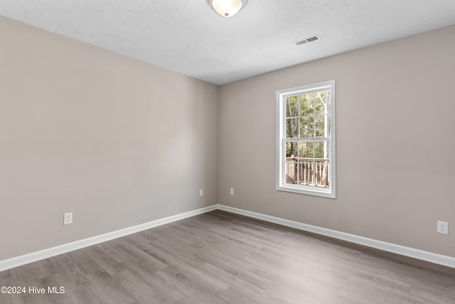 spare room with light wood-type flooring and a textured ceiling