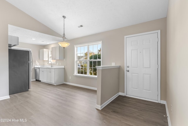 kitchen featuring stainless steel appliances, vaulted ceiling, sink, decorative light fixtures, and hardwood / wood-style flooring