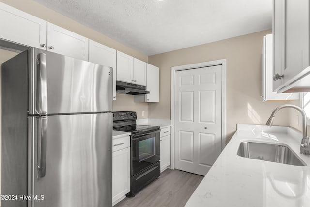 kitchen with black electric range, white cabinets, stainless steel refrigerator, and sink