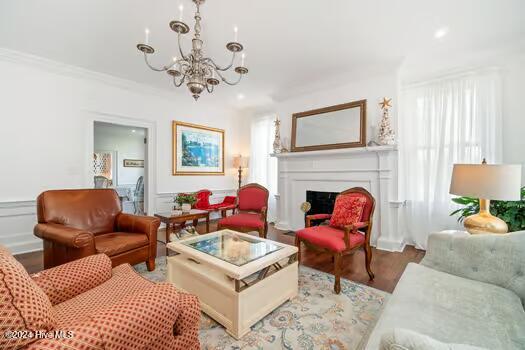 living room with a chandelier, hardwood / wood-style floors, ornamental molding, and plenty of natural light