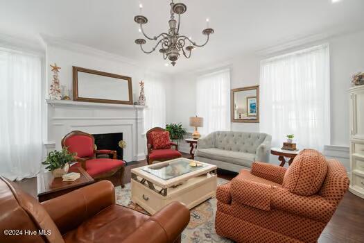 living room with wood-type flooring, a chandelier, and crown molding