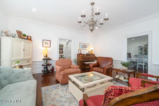 living room featuring hardwood / wood-style flooring, an inviting chandelier, and ornamental molding