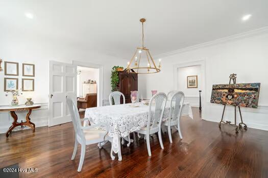 dining space featuring ornamental molding, dark wood-type flooring, and a chandelier