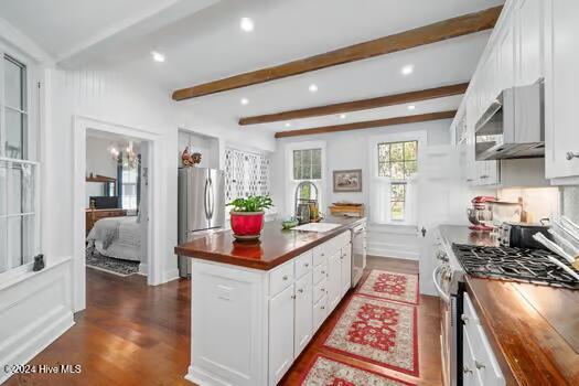 kitchen with white cabinets, appliances with stainless steel finishes, and beamed ceiling