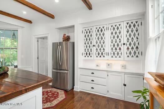 kitchen with white cabinets, dark hardwood / wood-style flooring, beamed ceiling, and stainless steel fridge