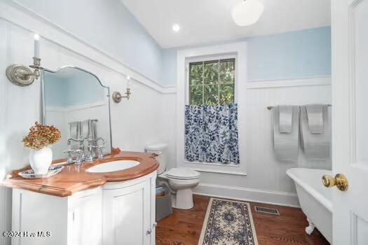 bathroom with vanity, hardwood / wood-style floors, toilet, a washtub, and lofted ceiling