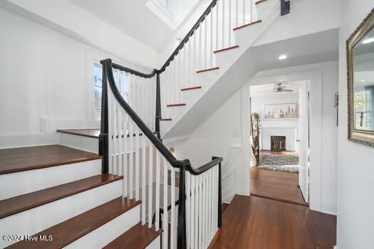 staircase with hardwood / wood-style floors and ceiling fan