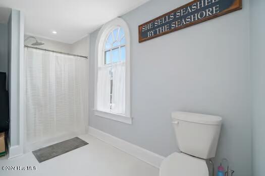 bathroom featuring toilet and curtained shower