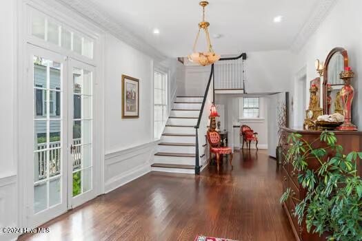 interior space with dark hardwood / wood-style flooring, a notable chandelier, crown molding, and plenty of natural light