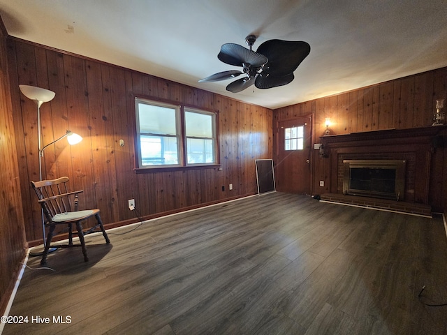 unfurnished living room with ceiling fan, wooden walls, a fireplace, and dark hardwood / wood-style flooring