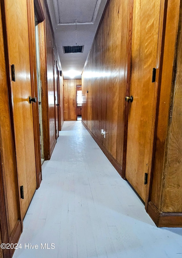 corridor with visible vents, wood walls, attic access, and light wood-type flooring