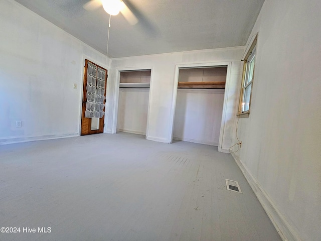 unfurnished bedroom with two closets and ceiling fan