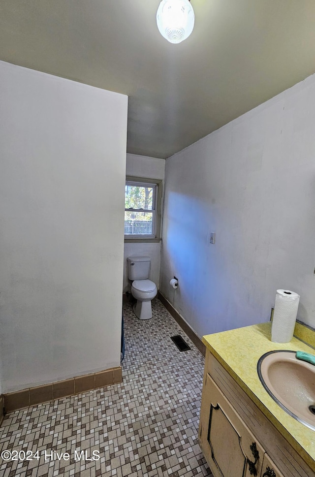 bathroom featuring visible vents, baseboards, toilet, and vanity