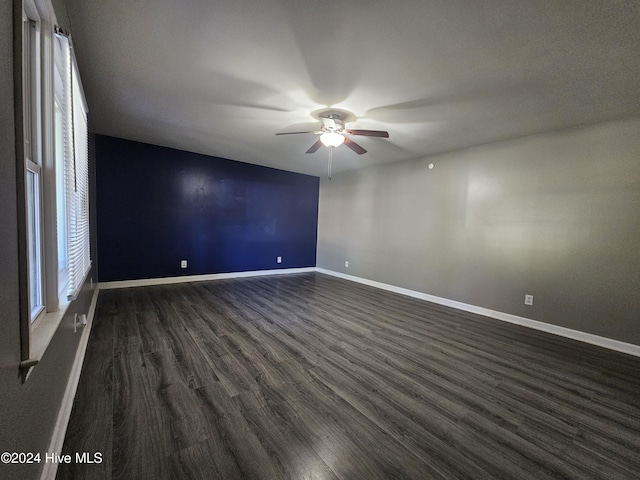 spare room with baseboards, dark wood-type flooring, and a ceiling fan