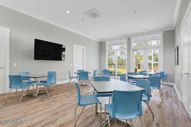 dining space with french doors, crown molding, and light hardwood / wood-style flooring