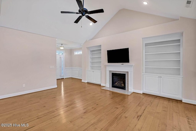 unfurnished living room with ceiling fan, high vaulted ceiling, a fireplace, built in shelves, and light wood-type flooring