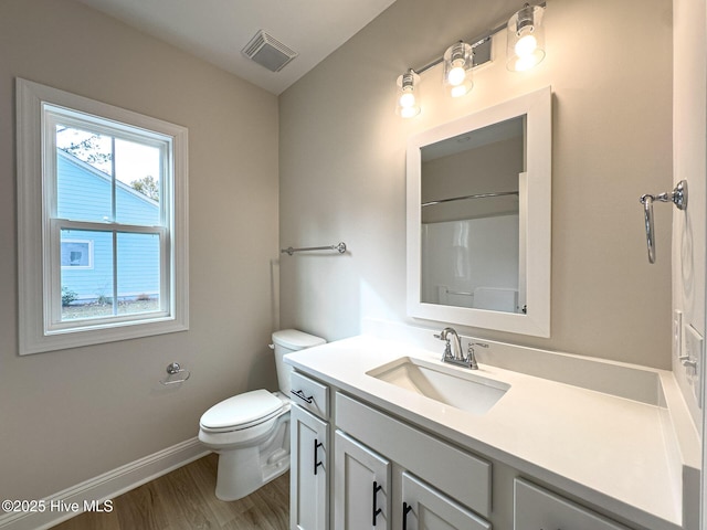 bathroom with hardwood / wood-style flooring, vanity, toilet, and walk in shower