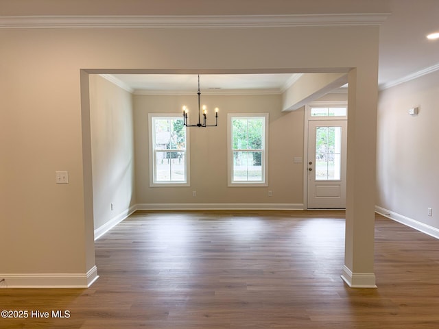 unfurnished dining area with ornamental molding, dark wood-type flooring, and an inviting chandelier