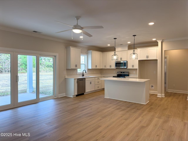 kitchen featuring white cabinetry, sink, decorative light fixtures, and appliances with stainless steel finishes