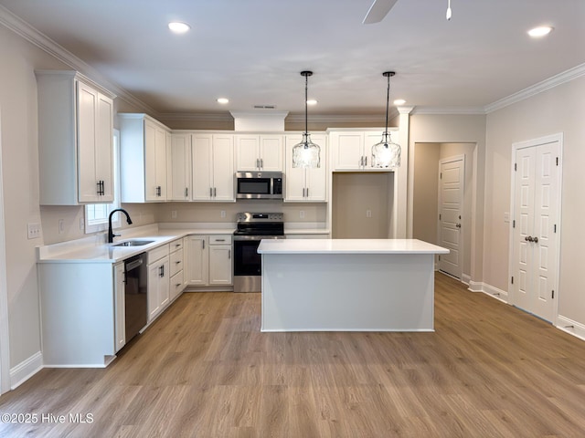 kitchen with sink, white cabinetry, decorative light fixtures, appliances with stainless steel finishes, and a kitchen island