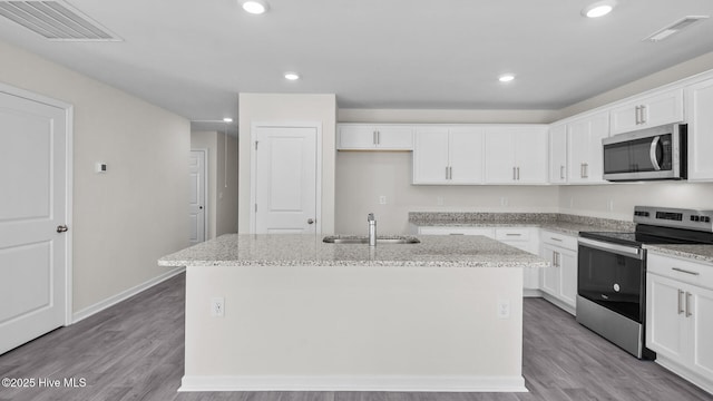 kitchen with stainless steel appliances, visible vents, a sink, and an island with sink