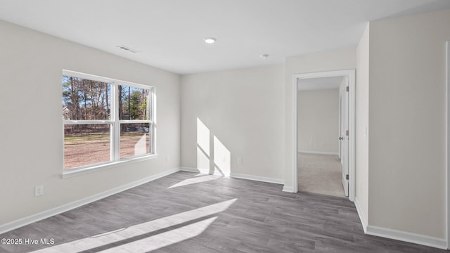 empty room featuring baseboards, visible vents, and wood finished floors