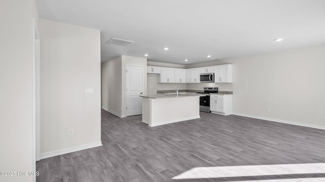 kitchen with white cabinets, open floor plan, wood finished floors, stainless steel appliances, and a sink