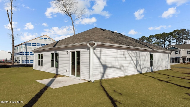 rear view of property featuring a shingled roof and a lawn