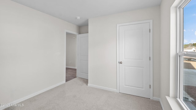 unfurnished bedroom featuring light carpet and baseboards