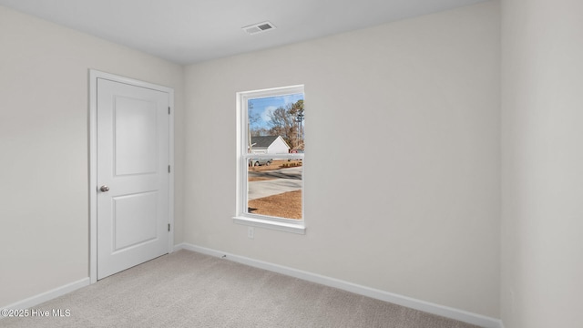 unfurnished room with light carpet, visible vents, and baseboards