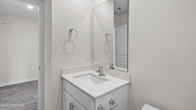 bathroom featuring toilet, wood finished floors, visible vents, vanity, and baseboards