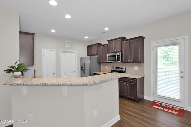 6639 Ramsey St, Fayetteville, NC 28311 - kitchen with appliances with stainless steel finishes, dark brown cabinets, a kitchen breakfast bar, dark wood-style floors, and a peninsula