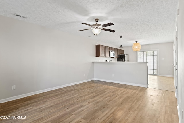 unfurnished living room featuring a textured ceiling, hardwood / wood-style flooring, and ceiling fan