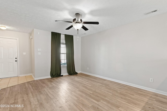 spare room featuring a textured ceiling, light wood-type flooring, and ceiling fan