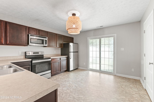 kitchen featuring dark brown cabinetry, hanging light fixtures, a textured ceiling, and appliances with stainless steel finishes