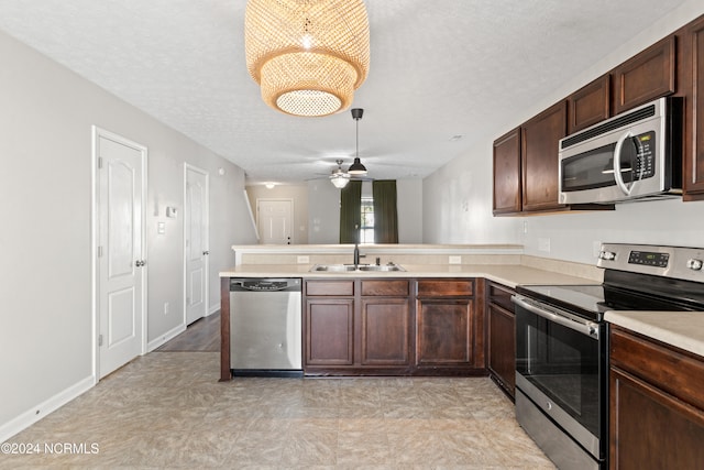 kitchen with a textured ceiling, kitchen peninsula, sink, and appliances with stainless steel finishes