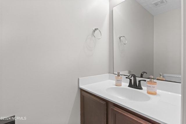 bathroom with vanity, toilet, and a textured ceiling