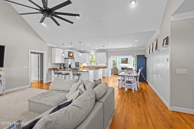 living room with sink, ceiling fan, crown molding, and light hardwood / wood-style flooring