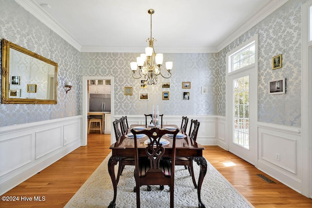 dining space with light hardwood / wood-style flooring, crown molding, and a notable chandelier